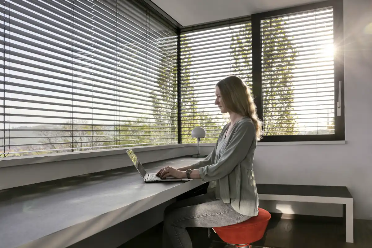 Produktives Arbeiten im modernen Büro Frau arbeitet an einem Laptop in einem modern eingerichteten Büro mit Jalousien