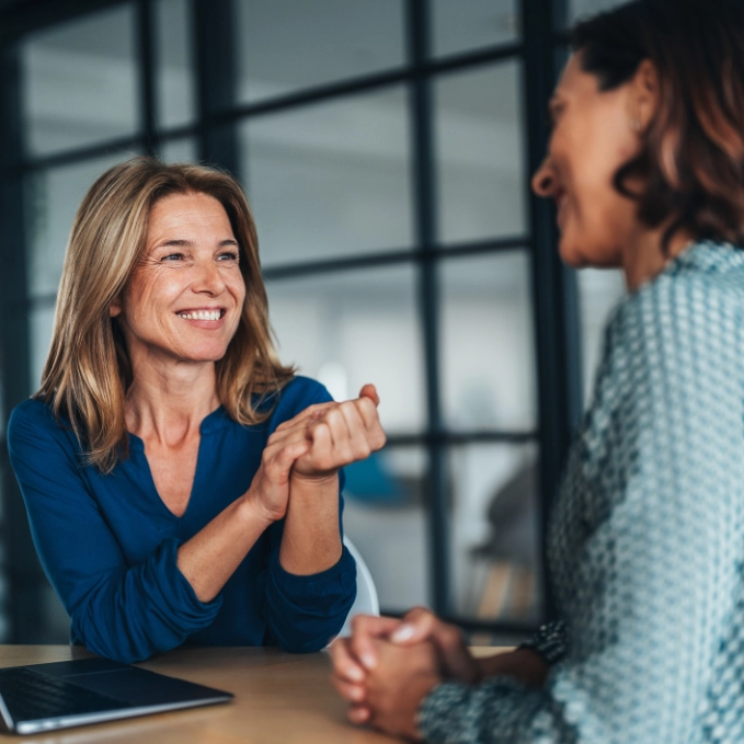 Sonnenschutz Beratung Zwei Frauen sitzen an einem Laptop und lächeln sich an