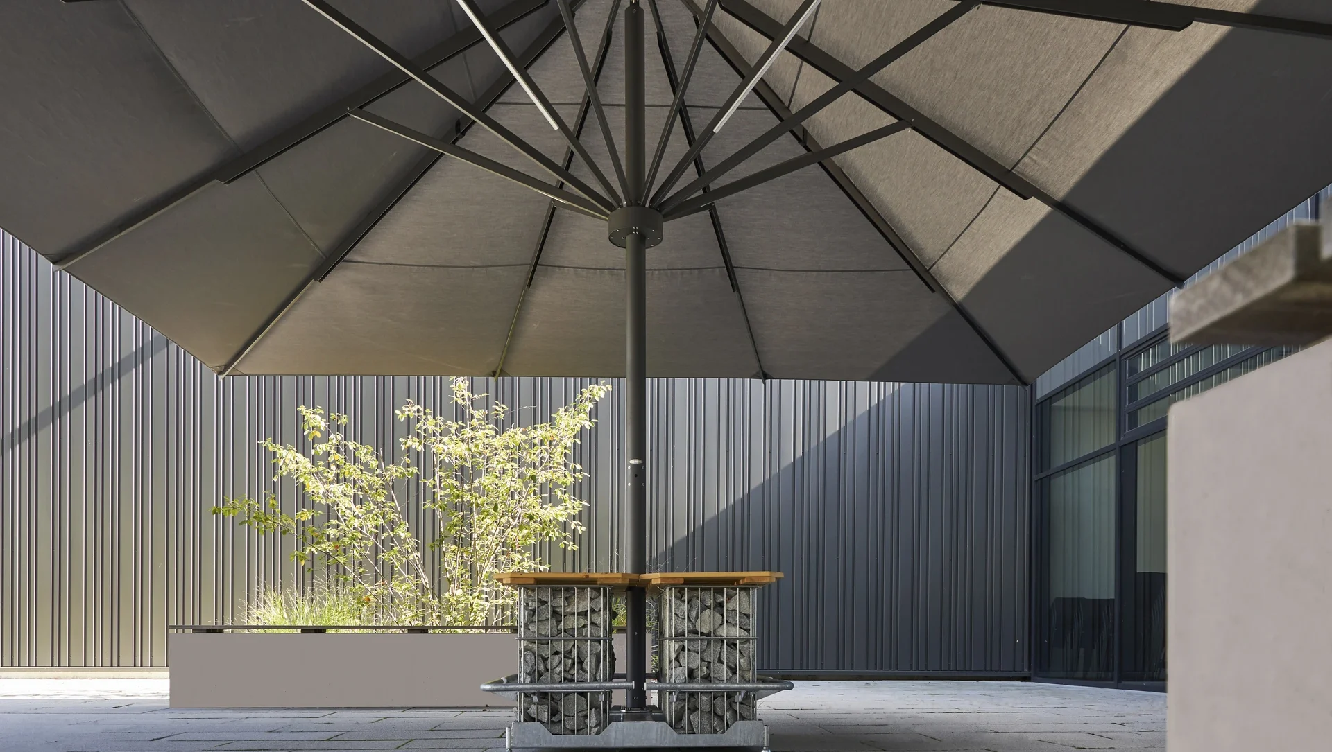 Moderner Außenbereich mit großem Sonnenschirm und Steintisch